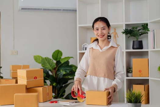 Young business entrepreneur sealing a box with tape. Preparing for shipping, Packing, online selling, e-commerce concept.