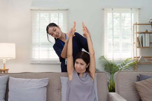 elderly Asian woman physical therapy with support of nurse or caregiver. Elderly woman doing exercises for patient with caregiver in home nursing.