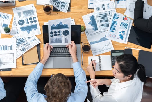 Top view diverse group of business analyst team analyzing financial data report paper on meeting table. Chart and graph dashboard by business intelligence analysis. Meticulous