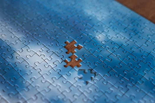 The missing piece of the sky puzzle, the concept of completing a big job, the final of the project, the successful solution of business problems. The hand puts the last piece of the jigsaw