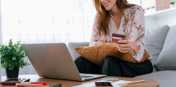 Young happy woman buy product by online shopping at home while ordering items from the internet with credit card online payment system protected by utmost cyber security from online store platform