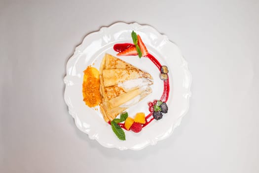 Isolated image of a gourmet pancake on a white plate with red sauce and berries, perfect for food blogs or recipe websites.