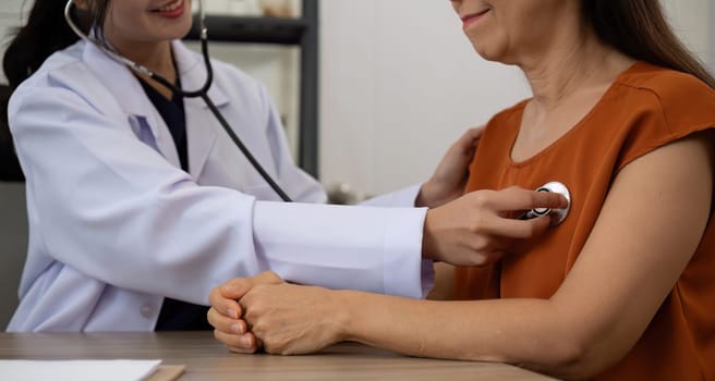 Female doctor and elderly female patient who are undergoing their annual health check-up at the clinic, using a stethoscope to examine patients.