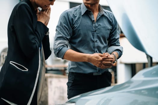 Man help woman fix the car problem. He pop up the car hood to repair the damaged part. uds