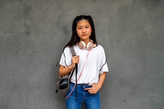 Teen Asian high school student girl standing outdoors looking at camera. Education and lifestyle concept.