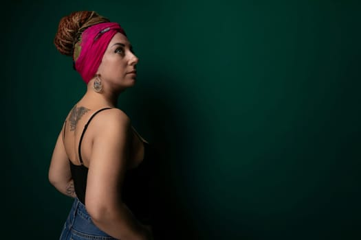 A woman wearing a pink headband stands against a vibrant green wall. The contrasting colors create a striking visual impact. The woman appears confidently posed in front of the wall, exuding a sense of style and individuality.