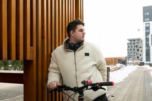 A young European man dressed in a winter jacket rented a bicycle for the weekend.