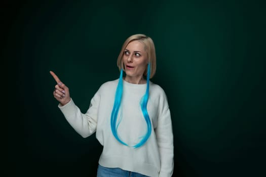 A woman with striking blue hair pointing at an unseen object with a serious expression. Her bold hair color contrasts with the background, drawing attention to the gesture she is making.