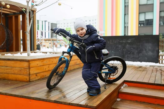 Child boy riding a bike in winter.