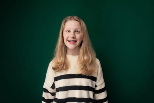 A girl wearing a black and white striped sweater, standing in front of a plain background, looking directly at the camera with a neutral expression.