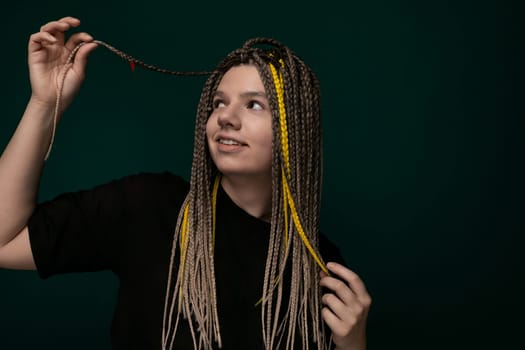 A woman with long dreadlocks stretching her arms above her head, holding her hair in the air. Her hair cascades down in thick, twisted strands.