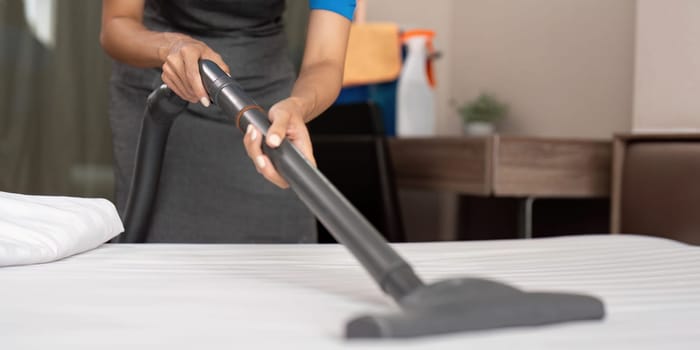 Cleaning service employee removing dirt from with professional equipment. Female housekeeper cleaning the mattress on the bed with vacuum cleaner.