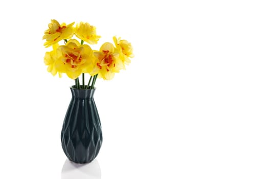 a still life with a blue vase with yellow daffodils with an orange heart on a white background isolated