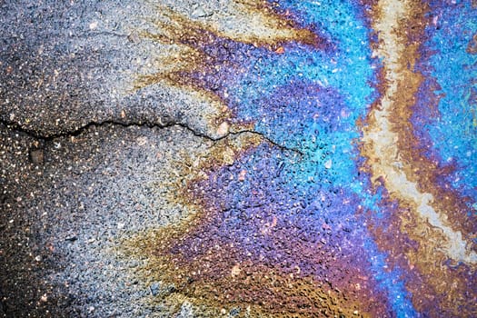 Rainwater mixes with oil residues, creating colorful patterns that shimmer in the sun.