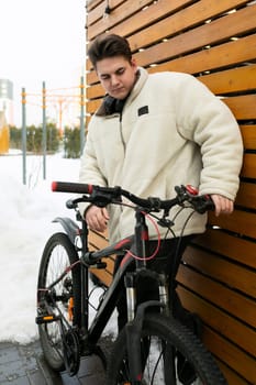Cute young guy riding a bike around the city in winter.