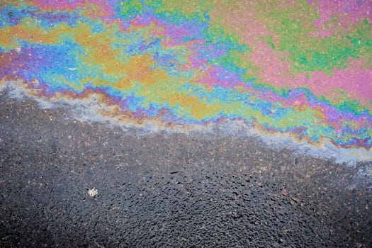 Color gasoline fuel spot on black asphalt, industrial pollution concept