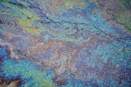 Marble spills on water from gasoline and oil stains. Abstract background from spilled motor oil, gas or gasoline on the asphalt.