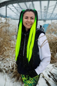 A woman with vivid green hair stands in the midst of a snowy landscape, her striking hair contrasting against the white snow. She gazes ahead, embodying a sense of strength and resilience in the cold winter setting.