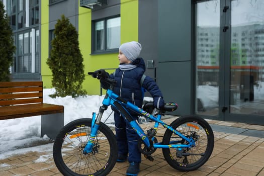 Little boy in snowsuit riding a bicycle.