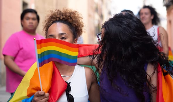 Lesbian girl hiding her face behind rainbow flag in a pride event. LGBTQ community support concept.