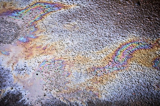 Rainbow reflections in the stains left by oil after rain