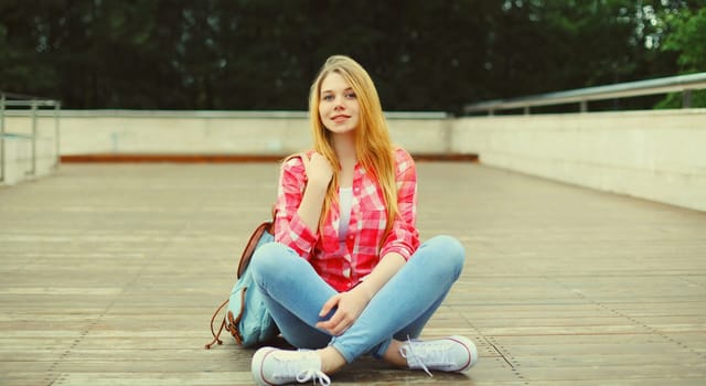 Happy caucasian teenager girl with backpack looking at camera posing on city street