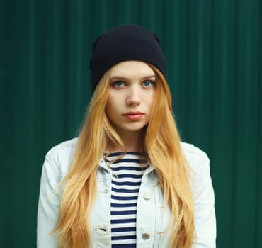 Modern caucasian teenager girl in black hat posing on city street