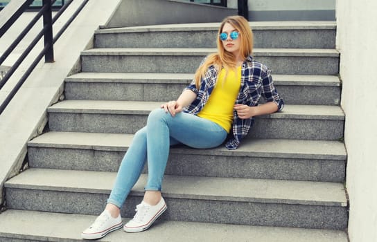 Modern caucasian teenager girl in sunglasses posing on city street