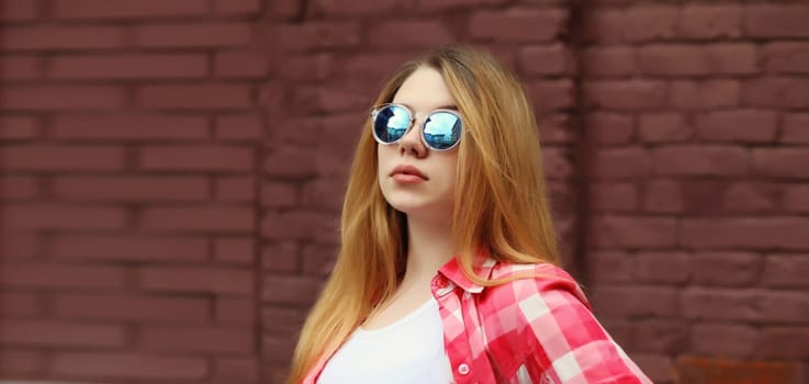 Modern caucasian teenager girl in sunglasses posing on city street