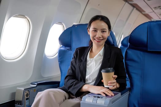 Young Asian woman sitting near the window on a business class airplane during a flight. Travel and business concept..