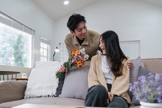 Young couple hugging and showing their love to each other. And give bouquets of flowers to each other on special days or Valentine's Day. On the sofa in the living room.