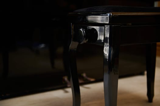 Details on a wooden and velvet backless stool near piano forte in the music class room. Stylish old-fashioned furniture. Close-up