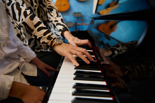 Close-up woman teacher hands touching piano keys while playing grand piano with her student boy in the music class. People. Leisure activity. Education. Childhood. Hobbies and kids entertainment