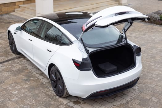 New white car open trunk. Electric car with open trunk. Modern electric vehicle. Car boot is open. Rear view of the car open trunk.