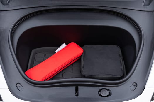 Front trunk or frunk under the hood lockable waterproof storage compartment of modern electric car parked outdoor. Car trunk for charging cables. Modern electric car with open trunk.