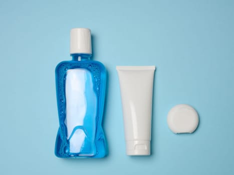 Mouthwash, toothpaste tube, dental floss  on a blue background, oral hygiene. Top view	
