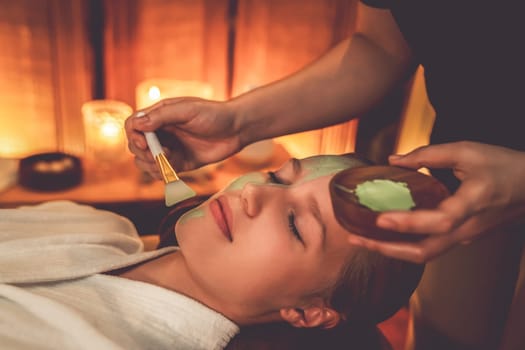 Serene ambiance of spa salon, woman customer indulges in rejuvenating with luxurious face cream massage with warm lighting candle. Facial skin treatment and beauty care concept. Quiescent