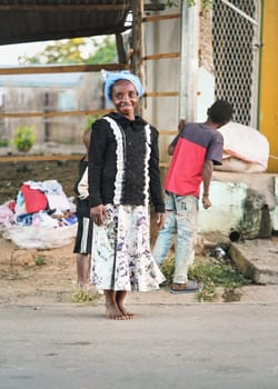Ranohira, Madagascar - April 29, 2019: Unknown Malagasy woman walking bare feet on main street, she stopped and turned to camera. People of Madagascar are poor but cheerful