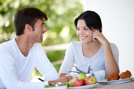 Couple, balcony and outdoors together for meal, love and affection in marriage or romance in nature. People, nutrition and smile at breakfast for healthy relationship, food and relax on vacation.