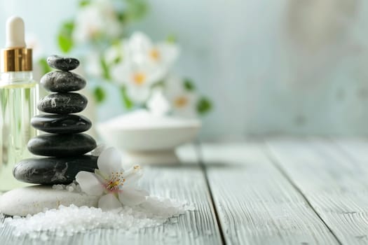 A serene arrangement of black zen stones piled atop each other, accompanied by a bottle of essential oil, on a wooden surface suggesting a tranquil spa setting.