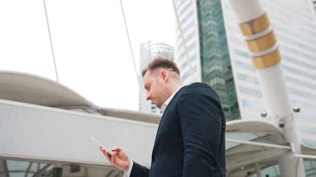 Caucasian business man checking mobile phone and looking report sales from marketing team while standing at urban city. Skilled manager working on mobile phone and looking at data analysis. Urbane.