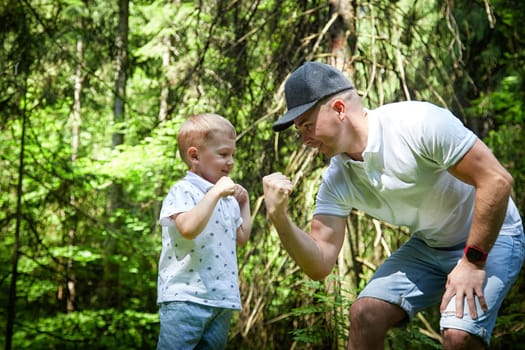 Father and Son Enjoying Playful Fist Bump in Lush Forest. A joyful moment as a dad and his young son exchange a fist bump in the woods
