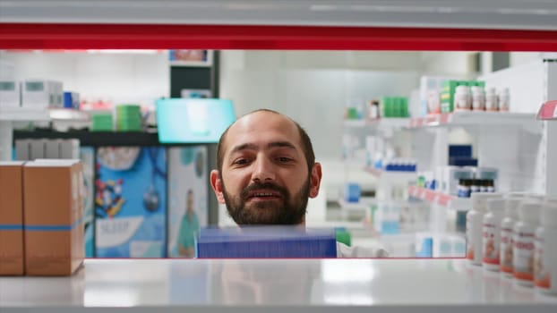 POV of pharmacist placing medicaments boxes on shelves, organizing types of medicine in pharmacy. Medical assistant putting supplements or treatments on prescription, insurance services. Tripod shot.