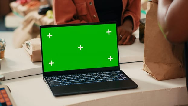 Greenscreen isolated display on laptop at farmers market, local vendor selling homegrown organic products at checkout. Woman buying fresh produce, blank chromakey copyspace template.