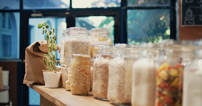 Local zero waste grocery store with bulk products in jars, empty supermarket isles. Additives free pasta, sauces and spices stored in recyclable glass containers on display. Handheld shot.