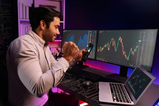 Smart trader businessman concentrating on dynamic stock exchange investment on pc and laptop showing on screen with high profit in searching market at neon light office in dark room night. Surmise.