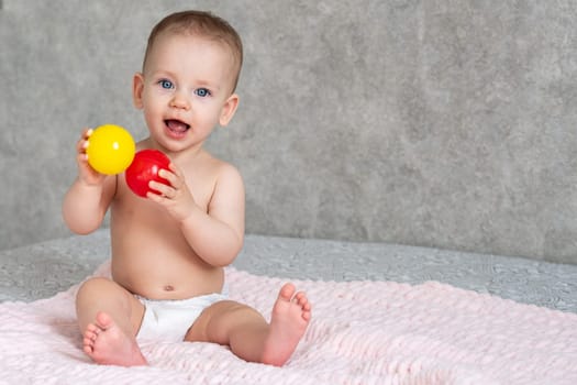 Little girl laughs and plays with yellow and red balls.