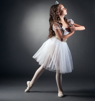 Side view of adorable little ballerina posing in studio