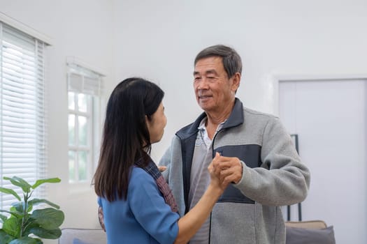 An elderly couple in their 60s happy danced together in the living room..