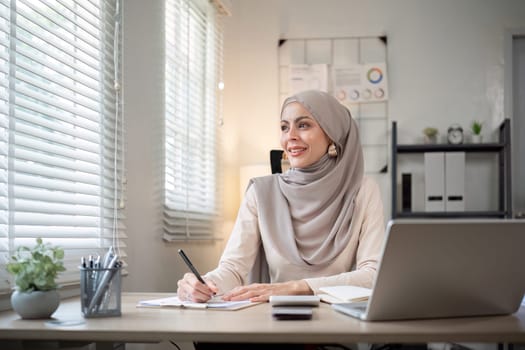 Attractive Muslim accounting business woman working using laptop in modern office.